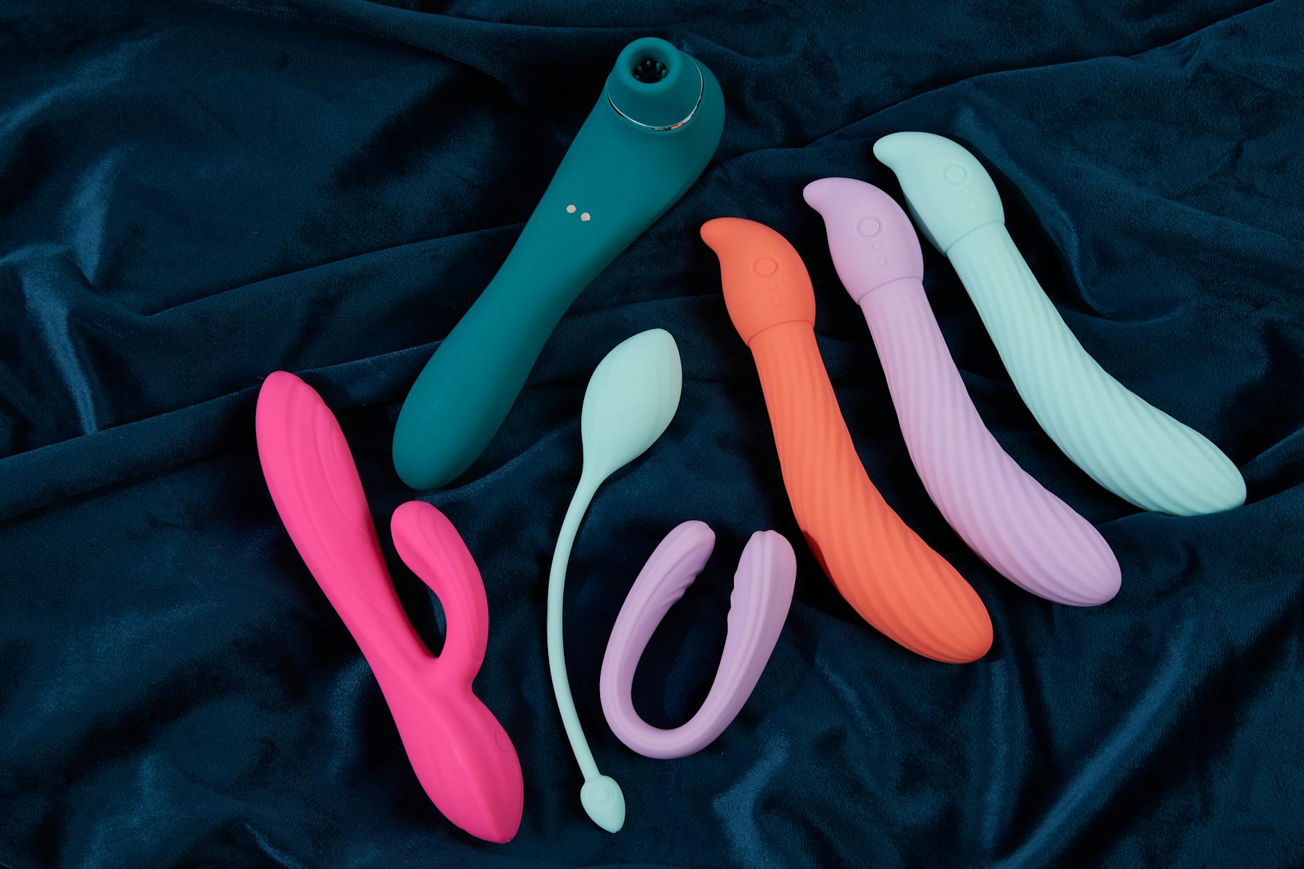 A hand holding an orange vibrator against a purple backdrop, showcasing modern sensuality and self-care