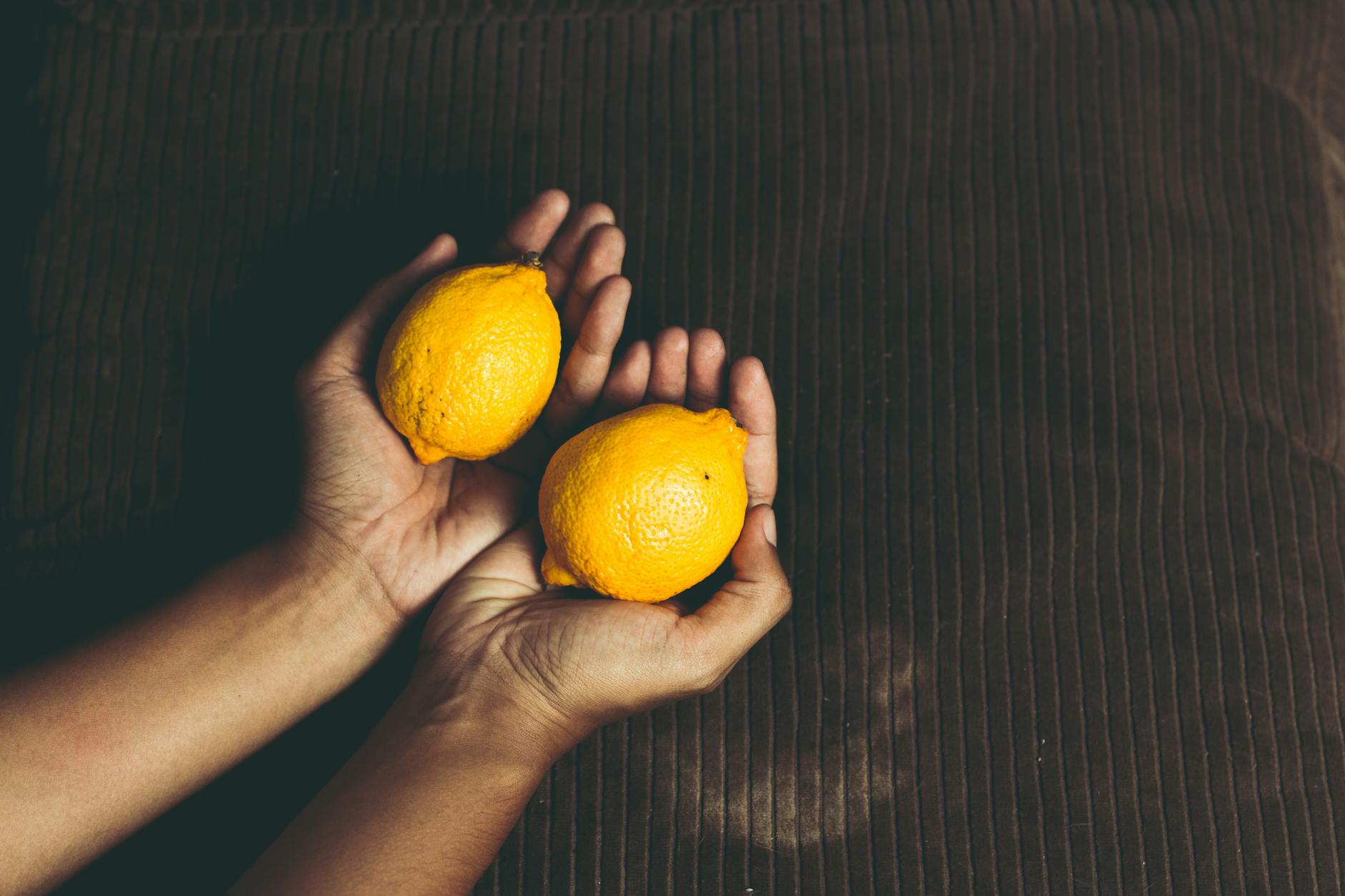 Two fresh lemons held in cupped hands, symbolizing safety and self-care