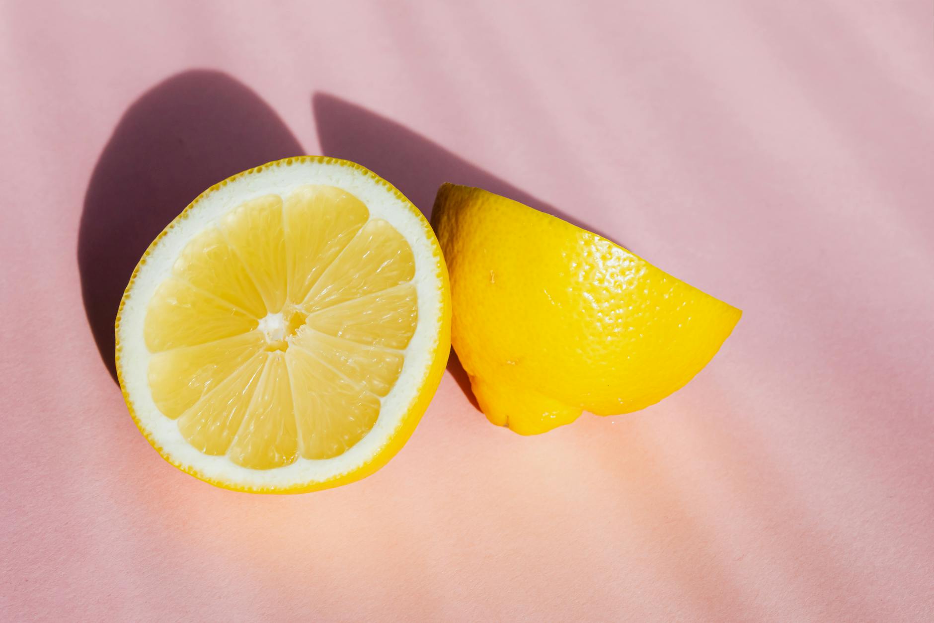 Fresh lemons on a bright pink background with natural sunlight