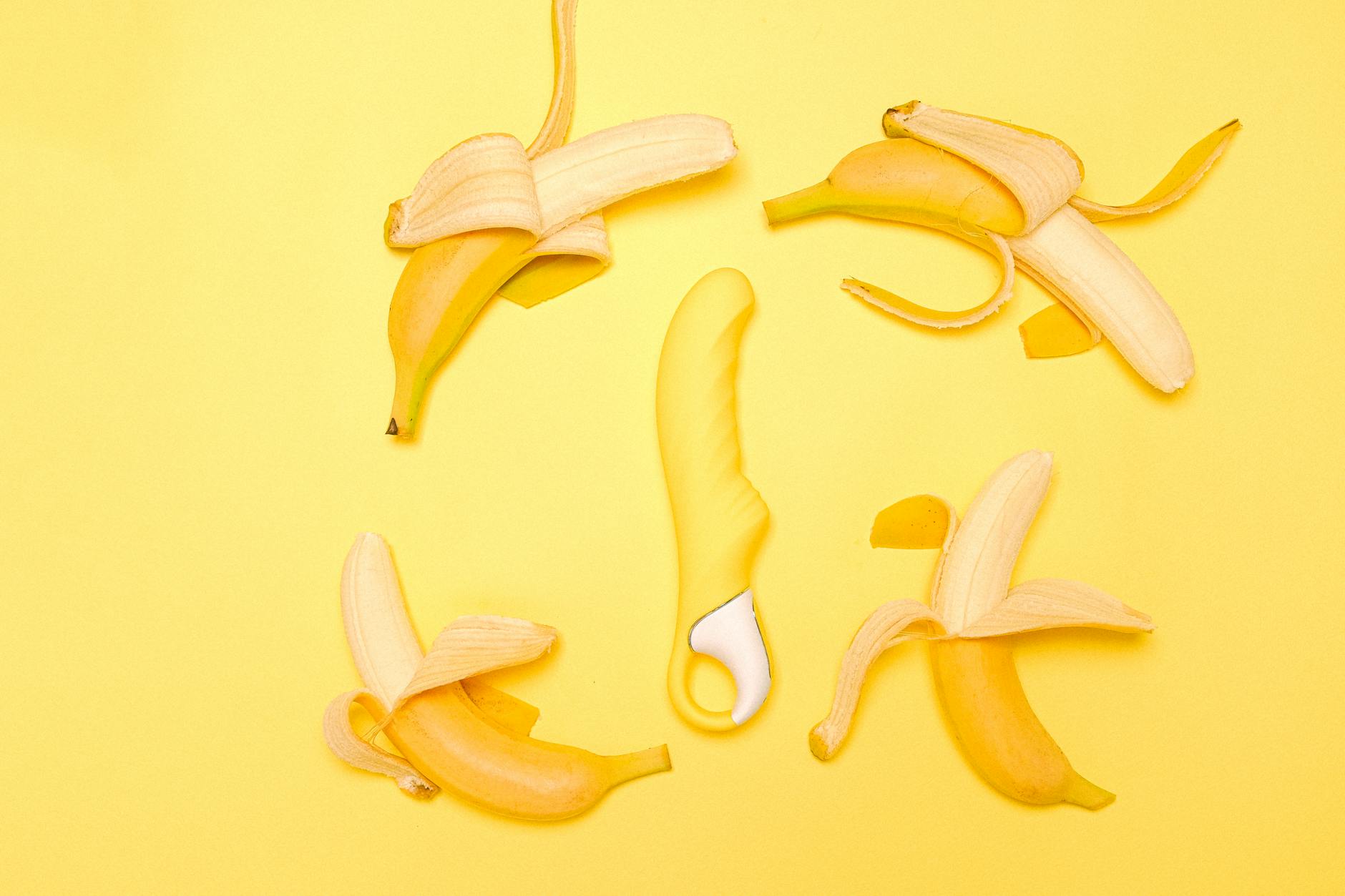 A yellow silicone lemon vibrator on a bright yellow background symbolizing self-care and pleasure