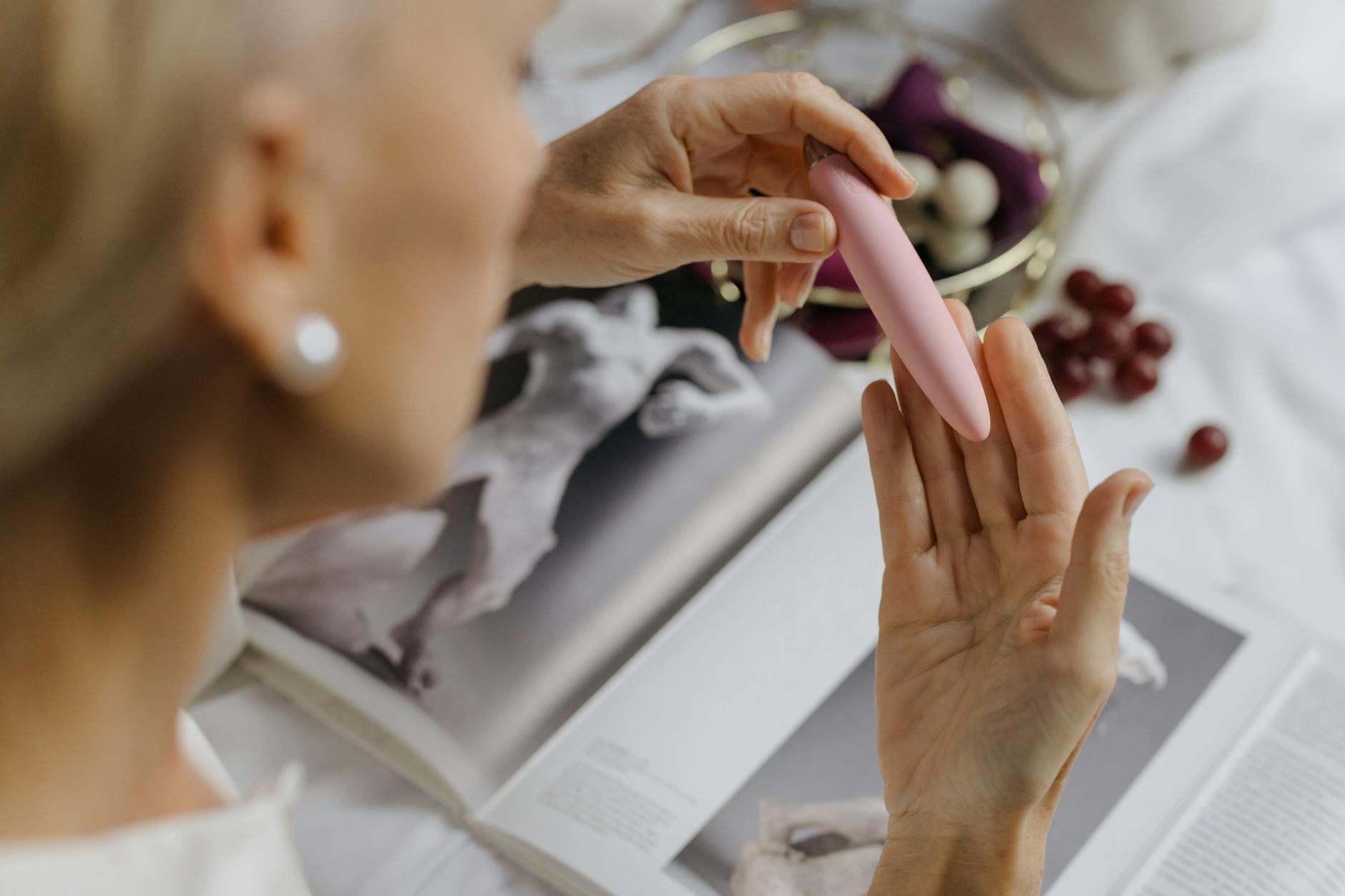 Close-up of a woman holding a lemon clitoral vibrator with personal wellness items in soft focus behind