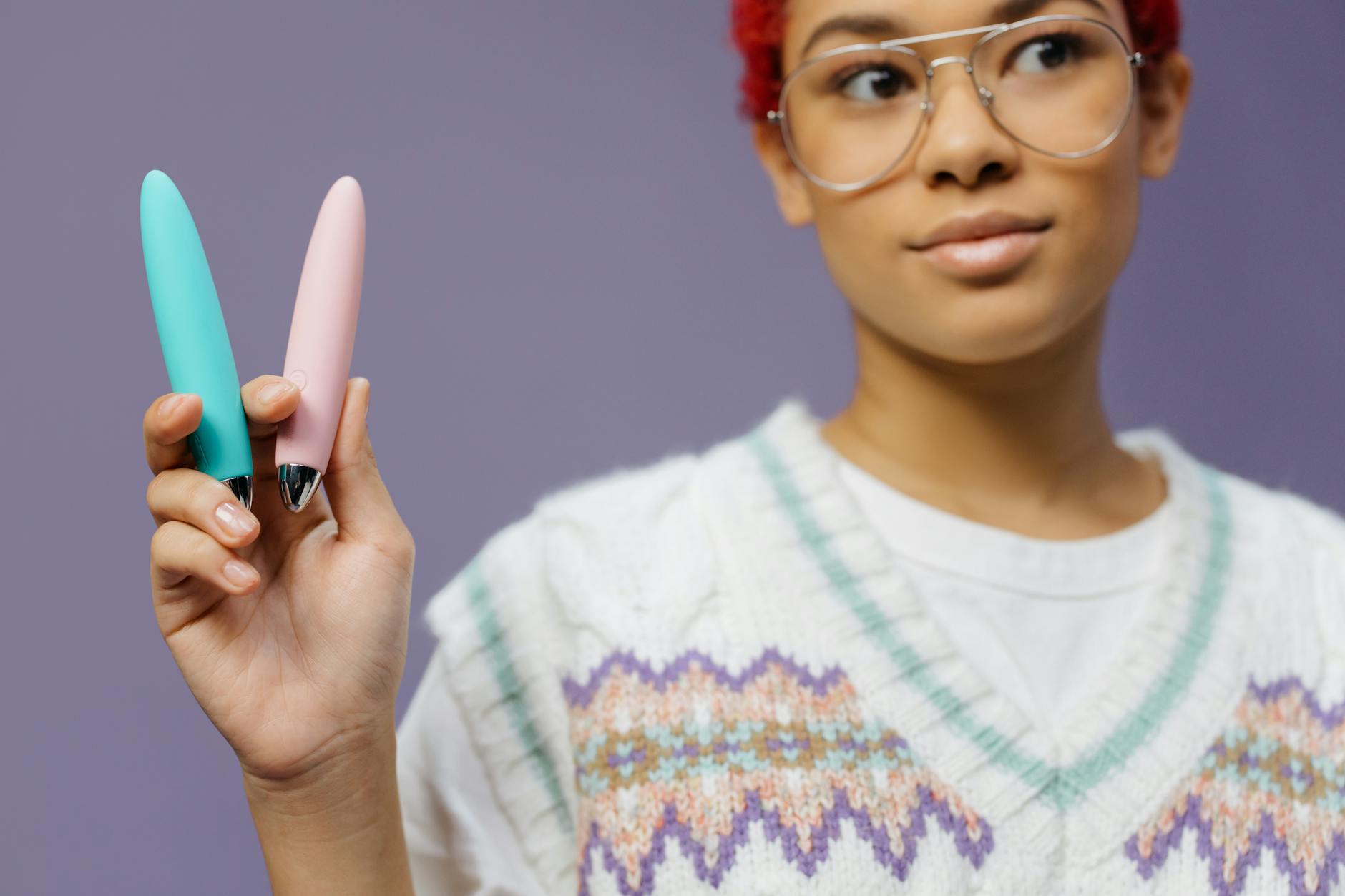 Two hands holding pink and blue silicone vibrators against a pastel background, symbolizing shared intimacy and reconnection.