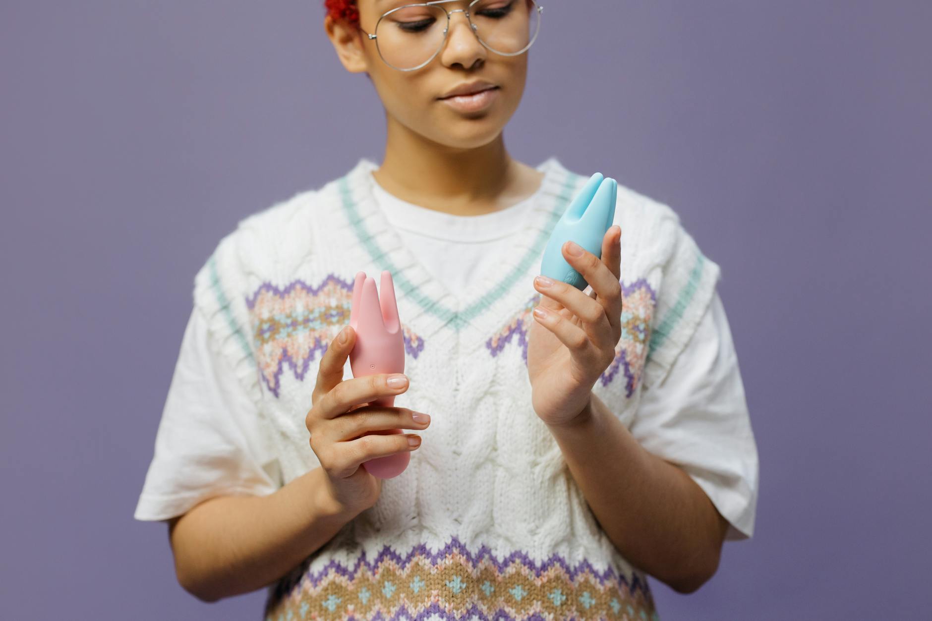 Hand holding a blue silicone lemon clitoral vibrator against a purple background