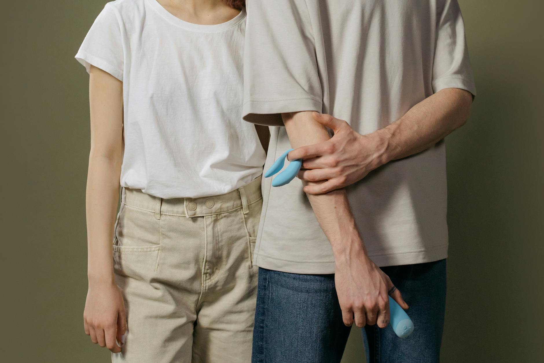 A young couple holding a blue vibrator together, symbolizing intimate exploration with birth control awareness